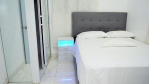 A bedroom with a bed, a nightstand, and a sliding door.