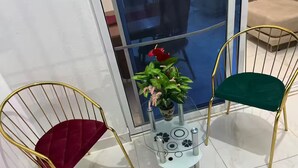A small, modern room with two chairs, a glass table, and a potted plant.
