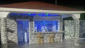 An outdoor bar area with a stone facade, wooden stools, and a counter.