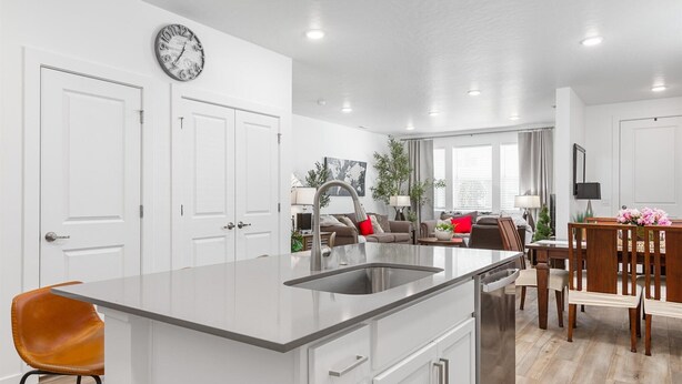 Una cocina moderna con una isla central, muebles blancos y un comedor con sillas y mesa de madera.