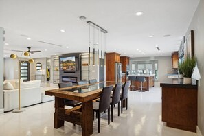 A modern kitchen with a central island, built-in appliances, and a dining area with a glass-top table.