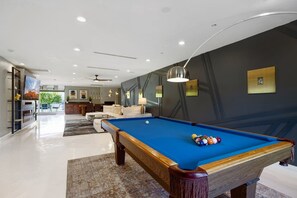 A modern living room with a pool table, a sofa, and a dining area. - Private Modern Home w Pool, Firepit & BBQ - Enjoy AZ outdoor living at its best! (Scottsdale)