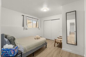 Une chambre à coucher comprenant un lit, une table de chevet, une chaise, une armoire et un miroir.