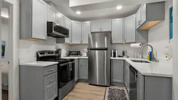 Una cocina moderna con armarios grises, electrodomésticos de acero inoxidable y suelo de madera.