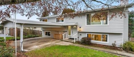 A two-story house with a covered driveway and a front yard.
