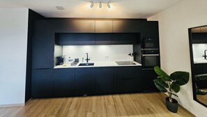 Una cocina moderna con armarios oscuros, encimera blanca y horno empotrado.