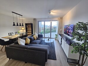 A modern living room with a sofa, dining table, and TV. - Serene 2 bedroom flat with terrace (Luxembourg City)