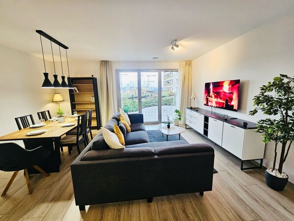 Uma sala de estar moderna com sofá, mesa de jantar e televisão.