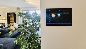 Una sala de estar con un sofá, una estantería y una planta grande.