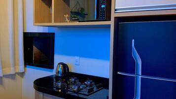 Cozinha compacta com micro-ondas, fogão e forno.