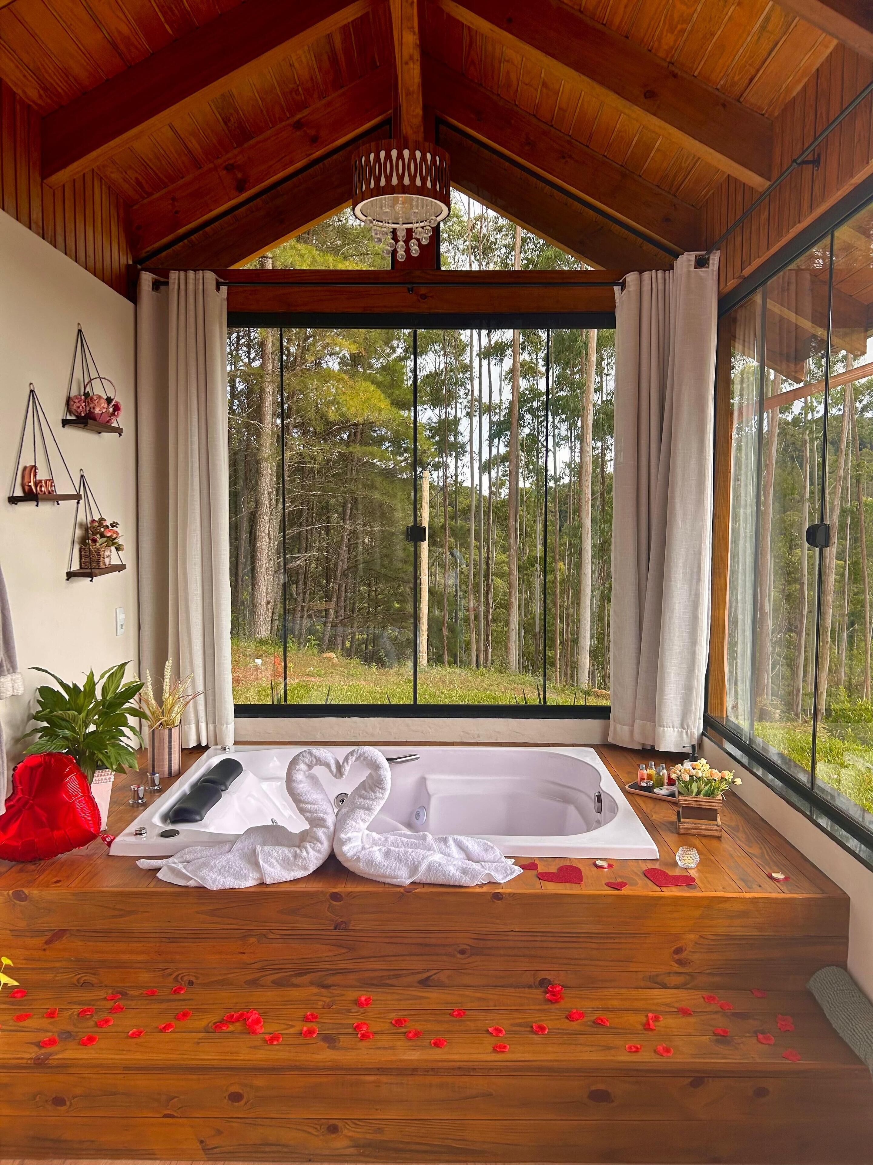 A wooden cabin with a large window, a bathtub, and a red chair.