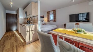 A modern kitchen with a built-in oven and microwave, a dining area with a yellow tablecloth, and a TV mounted on the wall.