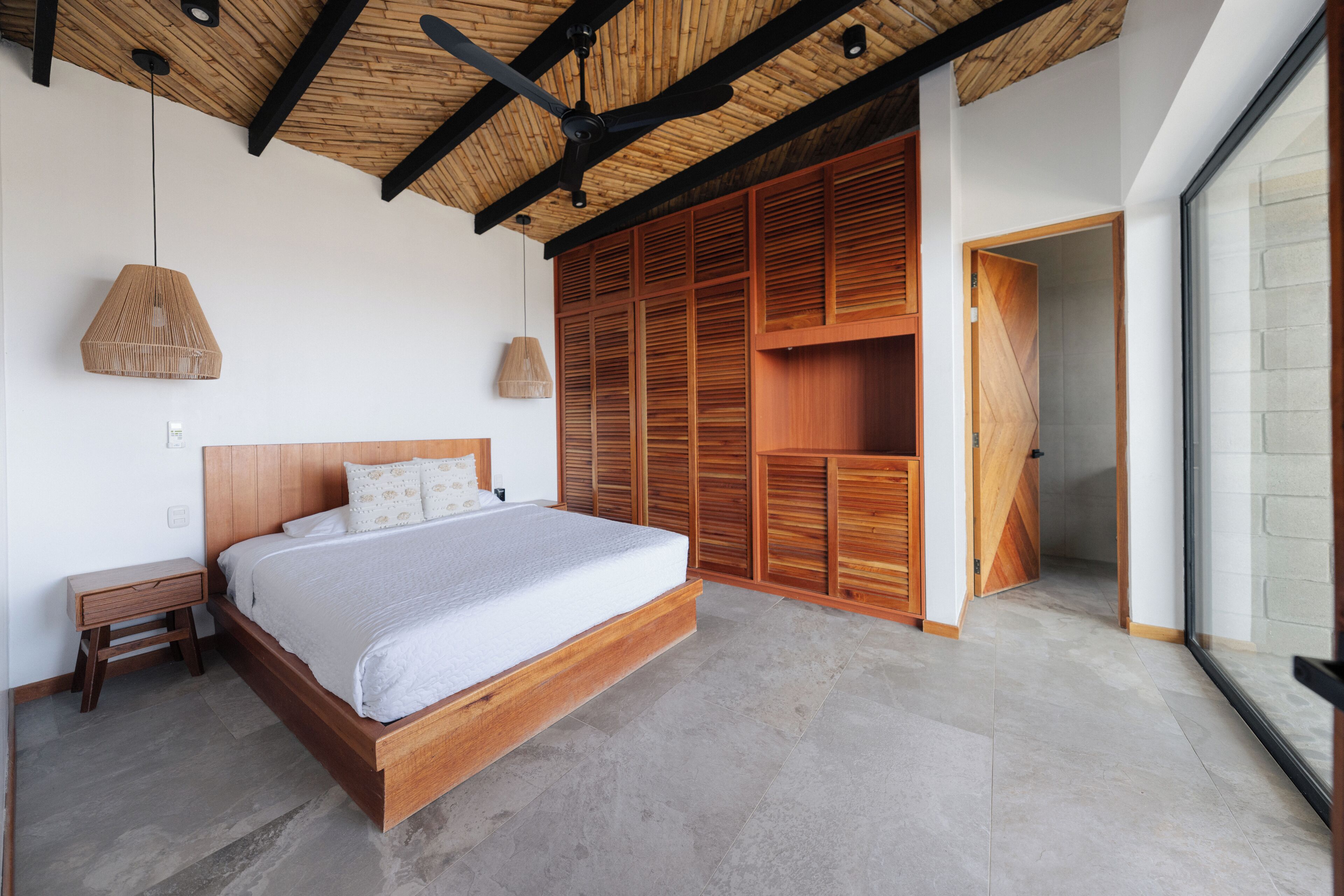 A bedroom with a wooden bed, a ceiling fan, and a large wardrobe.