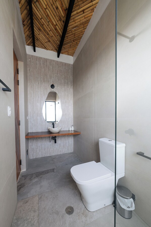 Uma casa de banho moderna com teto de bambu, sanita branca e um espelho grande.