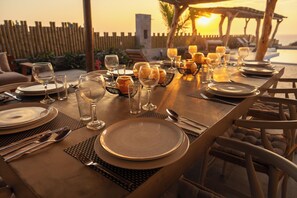 A table set for a meal with plates, glasses, and cutlery, overlooking a body of water at sunset. - Aviva, luxury de estreno en Vichayito (Vichayito)