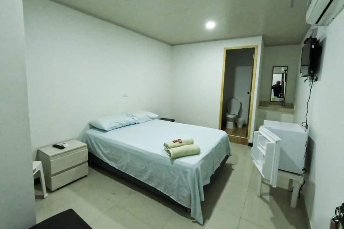 A bedroom with a bed, a nightstand, a dresser, and a mirror.
