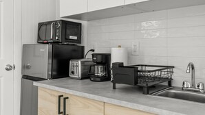 A compact kitchen with a microwave, toaster, coffee maker, and a sink with a dish rack. - Charming Studio Dennis Port Getaway with WiFi and AC - Close to Beach! (Dennis)