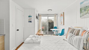 A bedroom with a bed, a chair, a table, and a sliding glass door leading to a balcony. - Charming Studio Dennis Port Getaway with WiFi and AC - Close to Beach! (Dennis)