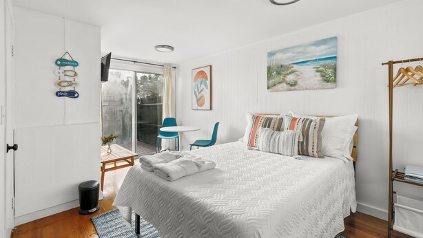A bedroom with a large bed, a window, a painting, and a wall-mounted towel rack. - Charming Studio Dennis Port Getaway with WiFi and AC - Close to Beach! (Dennis)
