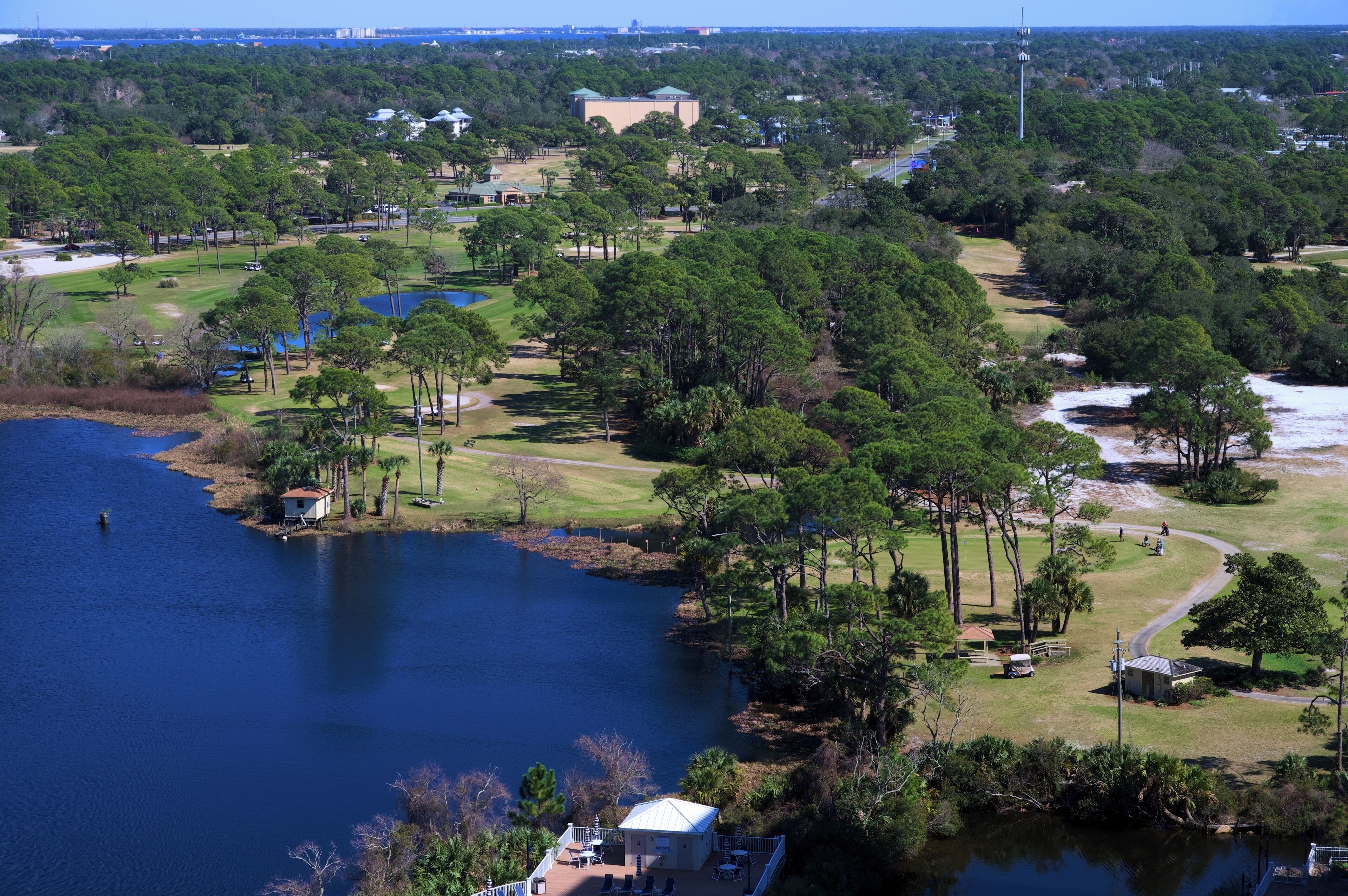 Un campo de golf con un lago, rodeado de árboles y edificios.