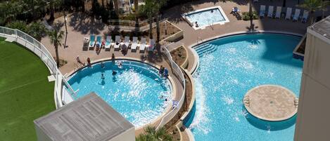 Una gran piscina al aire libre con múltiples zonas de solárium y una sección separada para adultos.