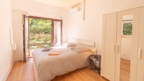 A bedroom with a bed, a bedside table, a wardrobe, and a sliding glass door leading to a balcony.