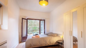 A bedroom with a bed, bedside table, and a view of the outdoors.