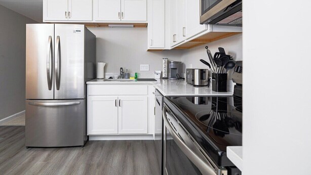 Una cocina moderna con armarios blancos, electrodomésticos de acero inoxidable y una estufa negra.