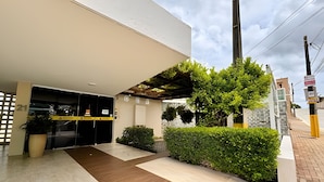 Une entrée moderne avec un passage couvert, un espace d’accueil et un jardin bien entretenu.