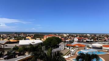 Um resort com piscina, espreguiçadeiras e vista para a cidade e o oceano.