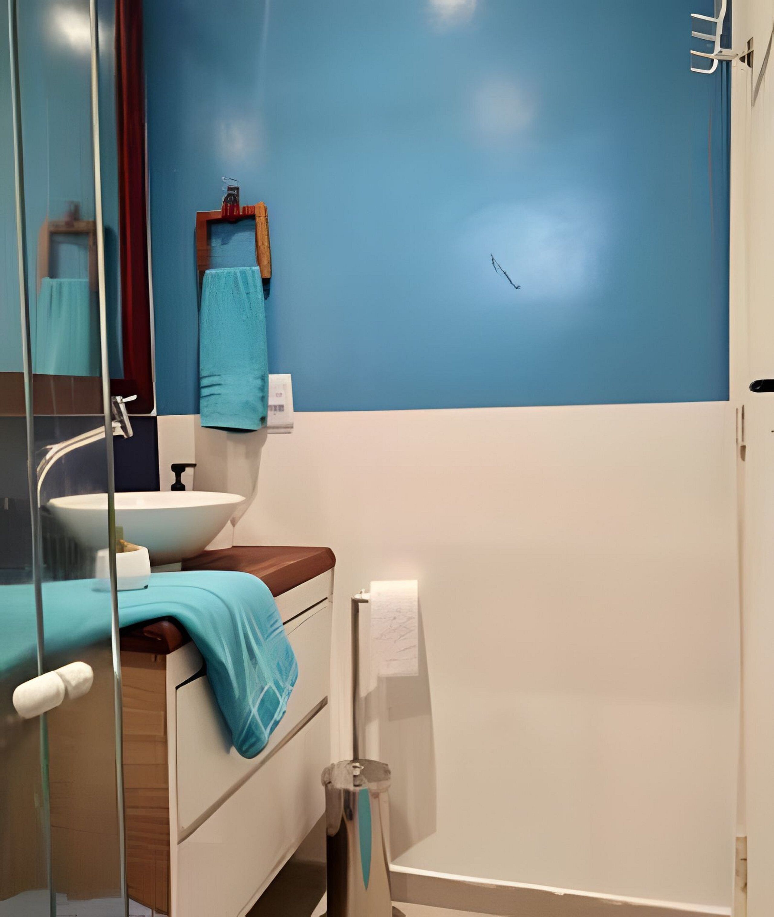 A bathroom with a blue wall, a white sink, a wooden countertop, a mirror, a towel rack, and a shower area.