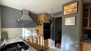 A kitchen with a granite countertop, a stainless steel range hood, wooden cabinets, and a black oven. - Sheffield's 3BR Retreat (Sheffield)