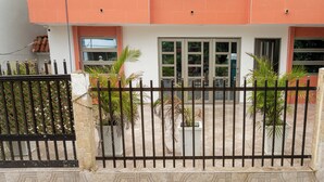 A gated entrance with a tiled patio, potted plants, and a building with orange and white walls. - Casa Sandunguera (Cartagena)