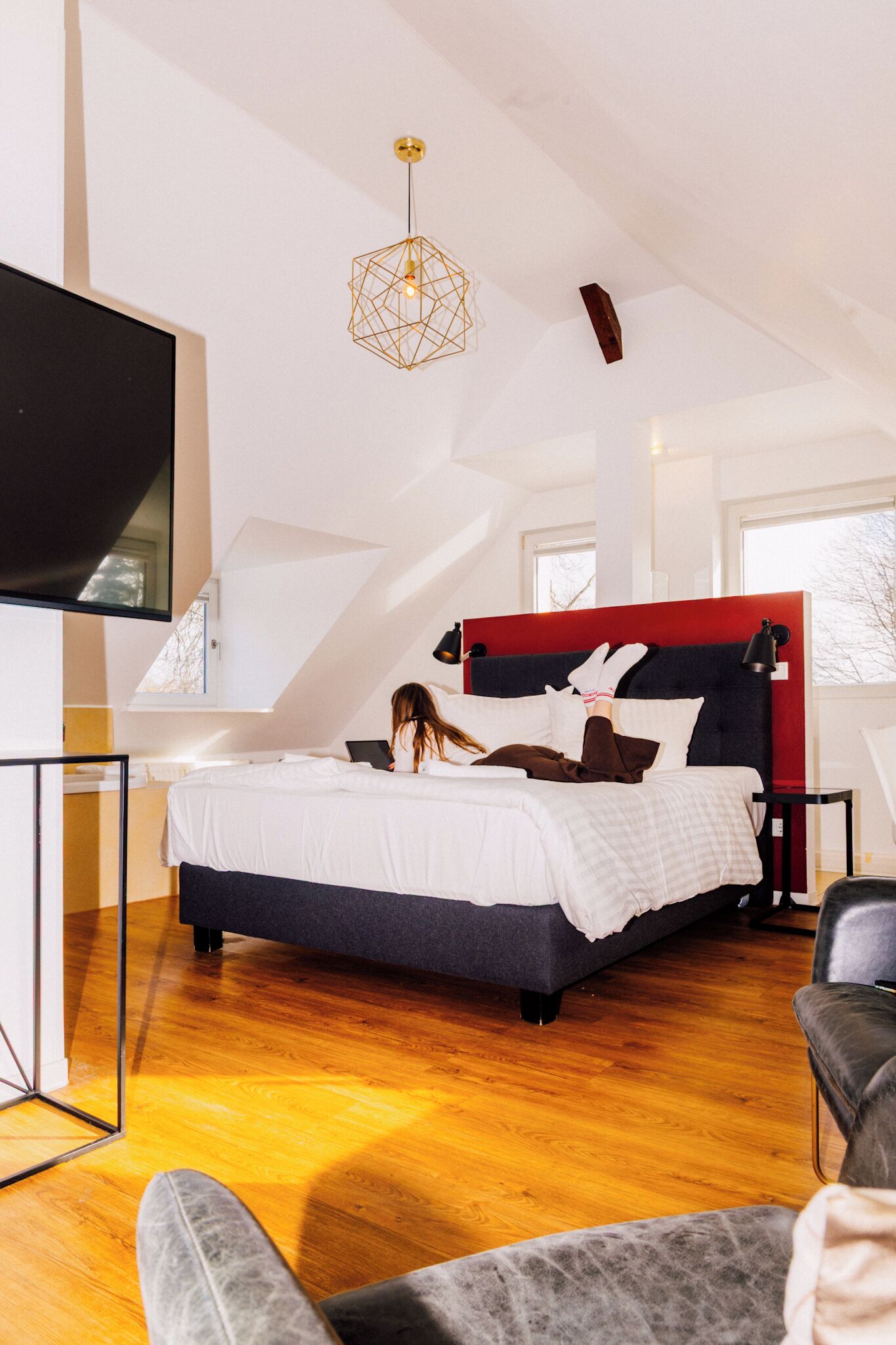 Ein modernes Schlafzimmer mit Bett, Schreibtisch und Fernseher.