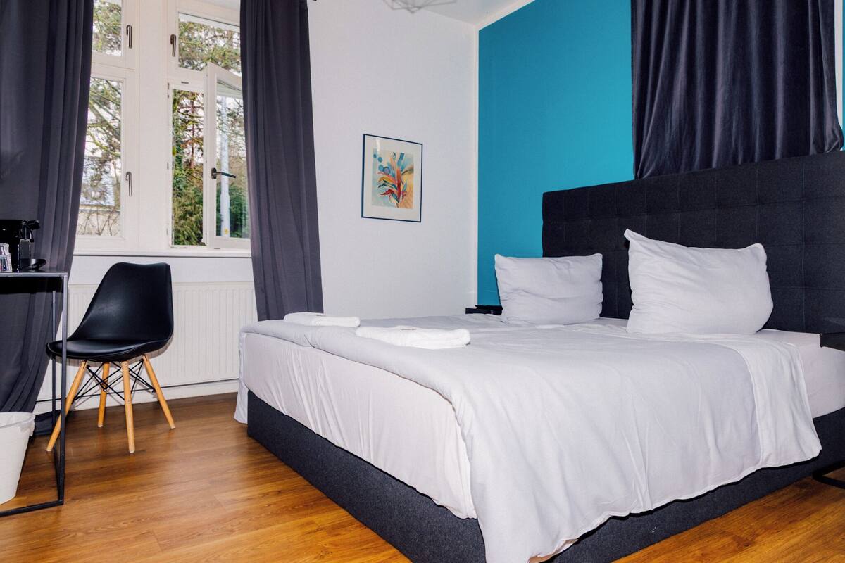 Ein Schlafzimmer mit einem Bett, einem Sessel, einem Fenster und einem Gemälde.