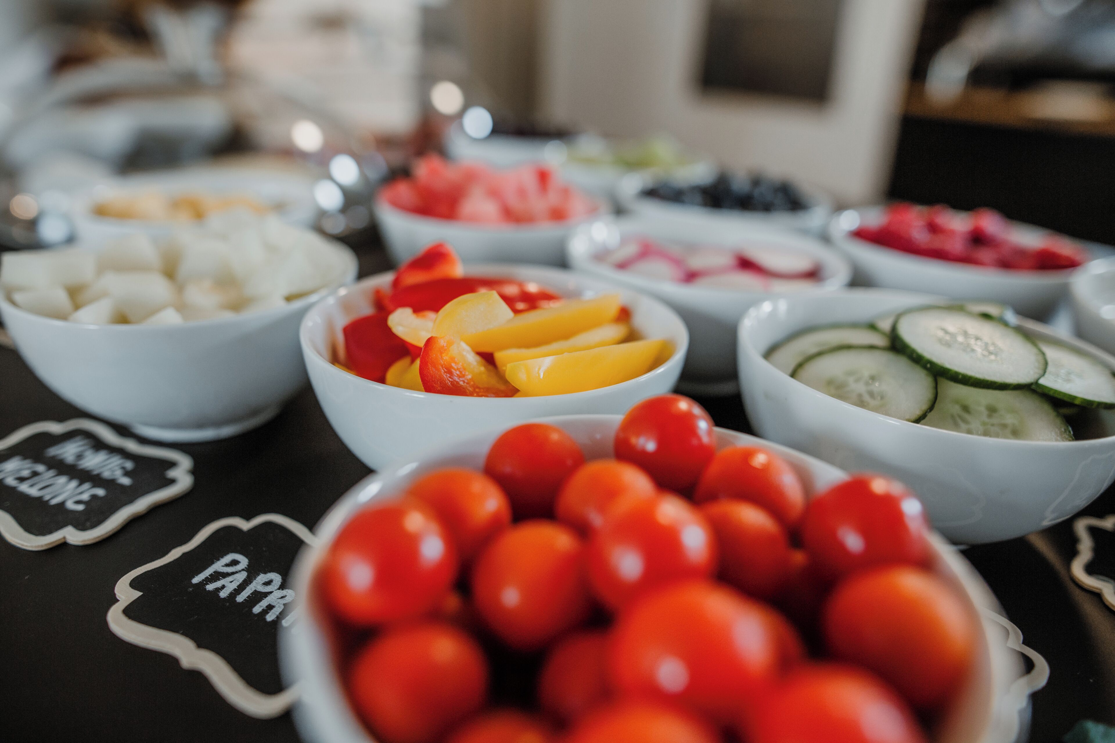 Verschillende schalen met fruit op een tafel, voorzien van labels.