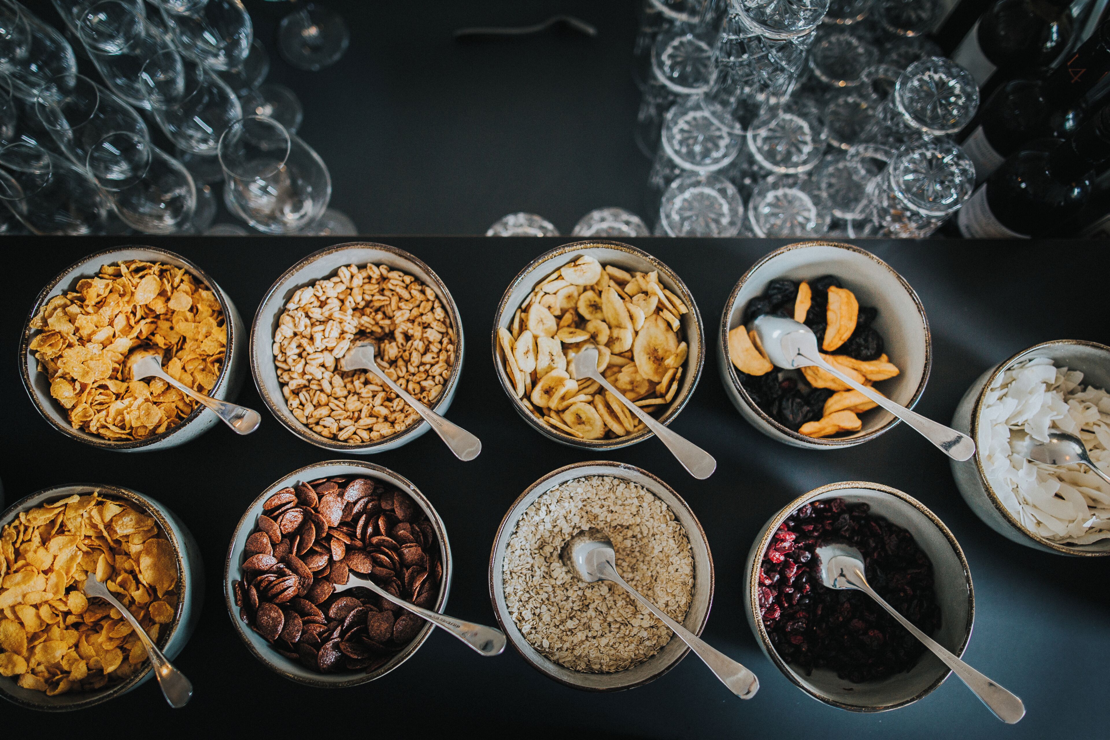 Variedad de tazones con diferentes alimentos y cucharas, dispuestos sobre una mesa.