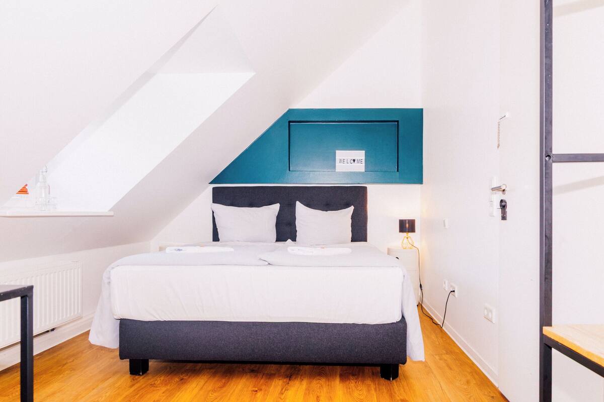 Ein Schlafzimmer mit Bett, einem 'WELCOME'-Schild, einem Oberlicht und Holzboden.