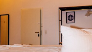Een slaapkamer met een bed, een deur en een wandlamp.