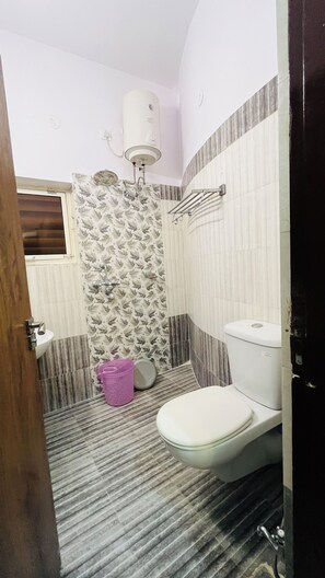 Een badkamer met een toilet, douche en wastafel.