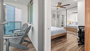 Ein modernes Hotelzimmer mit Balkon, Bett, Schreibtisch und Deckenventilator.