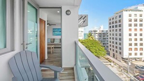 Ein Balkon mit Blick auf eine Stadtlandschaft, eine Holztür und eine Sitzecke mit Sofa und Tisch.
