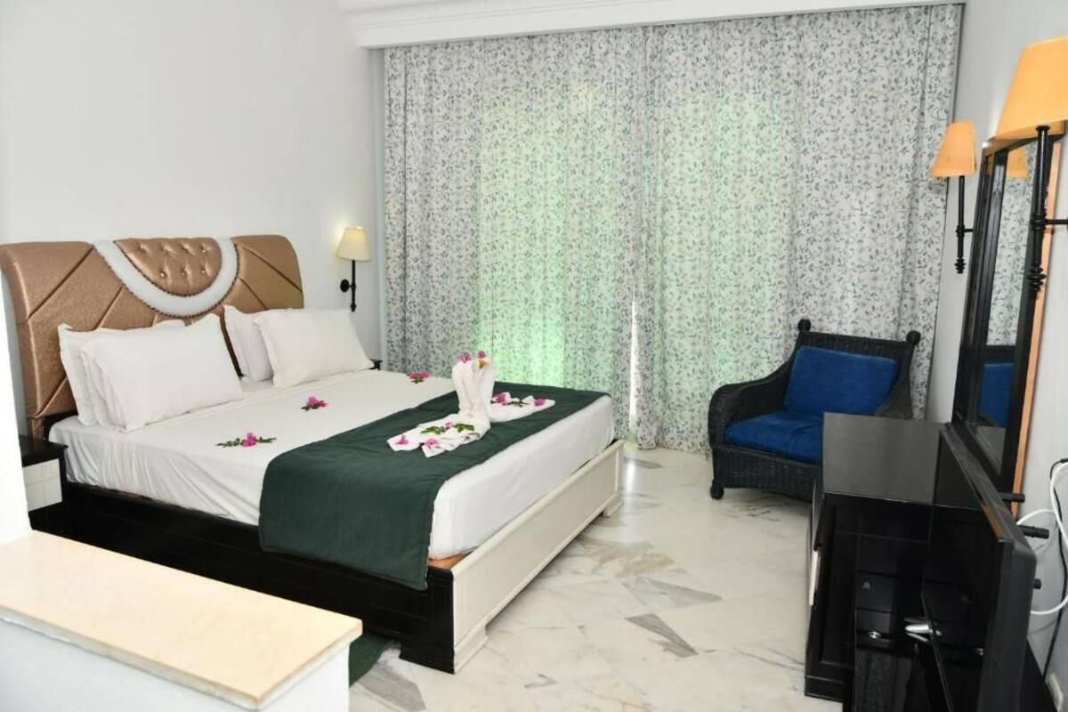 Una habitación de hotel con una cama, una silla, un escritorio y un televisor.
