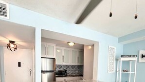 A kitchen with a bar area, wooden stools, and a white cabinet. - Beachfront Paradise @ Coral Beach,  Isla Verde (Carolina)