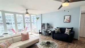 A modern living room with a large sofa, a coffee table, and a ceiling fan. - Beachfront Paradise @ Coral Beach,  Isla Verde (Carolina)