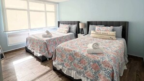 A bedroom with two beds, a ceiling fan, and a large window. - Beachfront Paradise @ Coral Beach,  Isla Verde (Carolina)