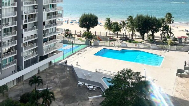 A high-rise hotel with a pool area, beach view, and multiple balconies. - Beachfront Paradise @ Coral Beach,  Isla Verde (Carolina)