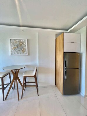 A modern kitchen with a stainless steel refrigerator, a wooden cabinet, and a round table with two chairs.