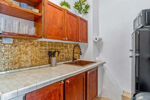 Une cuisine avec des meubles en bois, un pare-feu en carrelage et un réfrigérateur noir.