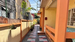 A narrow alleyway with tiled flooring, potted plants, and a yellow wall. - Chic 2-bedroom apartment with WiFi, fitness room in vibrant Vacoas-Phoenix (Vacoas-Phoenix)